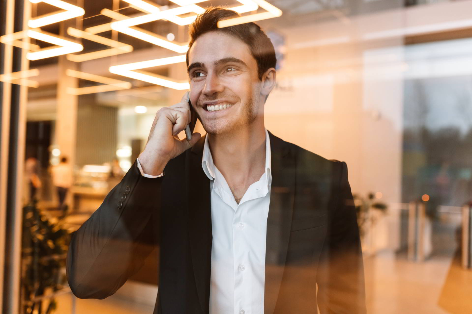 smiling business suit talking phone behind glass looking aside