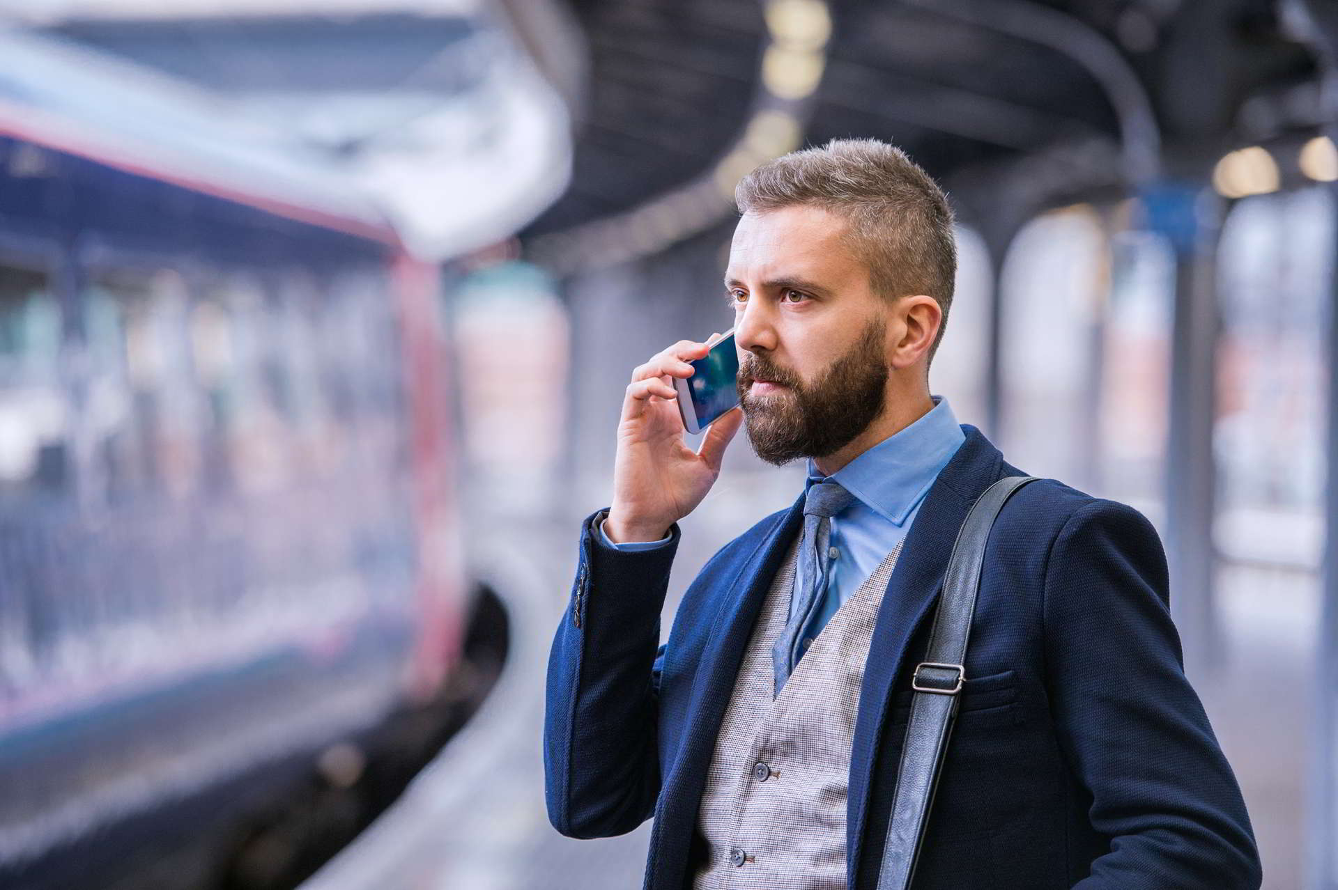 hipster businessman with smartphone making phone call walking train station