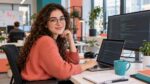 Entwicklerin mit Brille am Laptop und zweiten Bildschirm im Büro